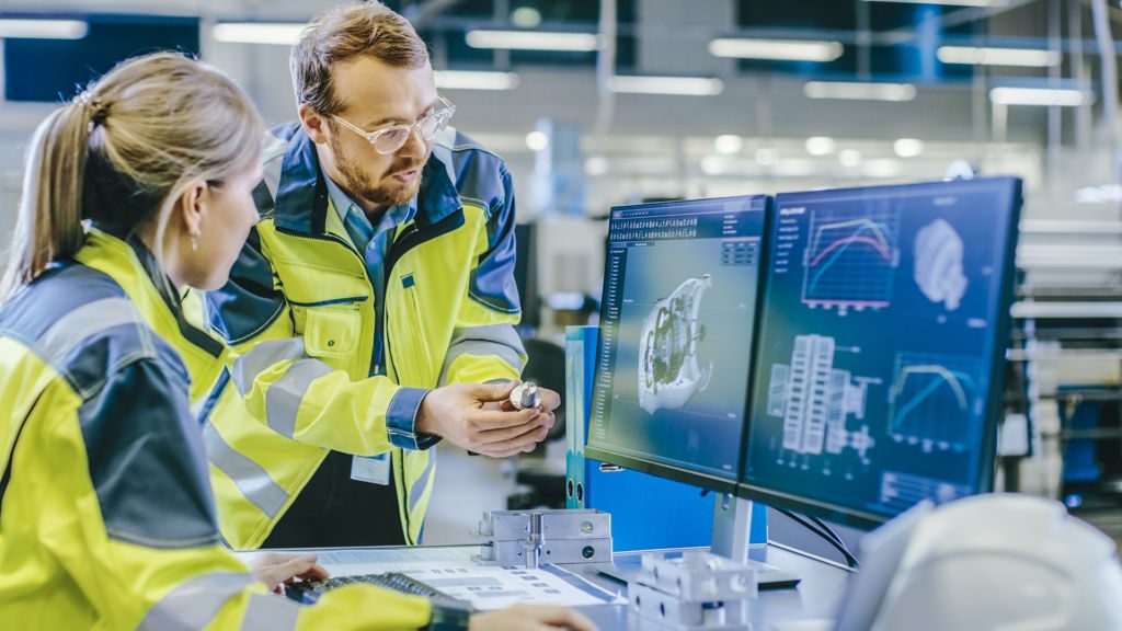 At the Factory: Male Mechanical Engineer Holds Component and Female Chief Engineer Work on Personal Computer, They Discuss Details of the 3D Engine Model Design for Robotic Arm.